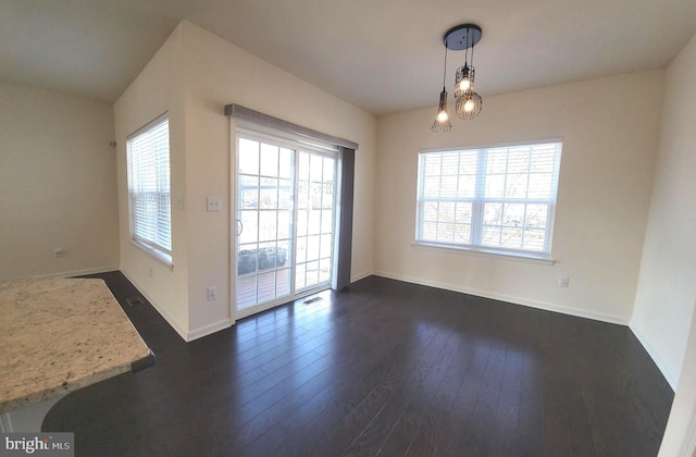 unfurnished dining area featuring plenty of natural light, visible vents, baseboards, and dark wood finished floors