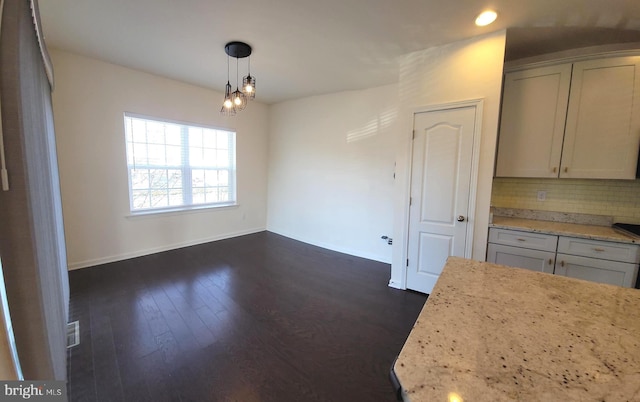 unfurnished dining area featuring dark wood-style floors, visible vents, and baseboards