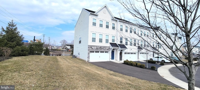 multi unit property featuring a garage, driveway, stone siding, central AC, and a front yard