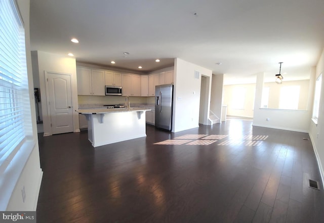 kitchen featuring visible vents, appliances with stainless steel finishes, a breakfast bar, open floor plan, and light countertops