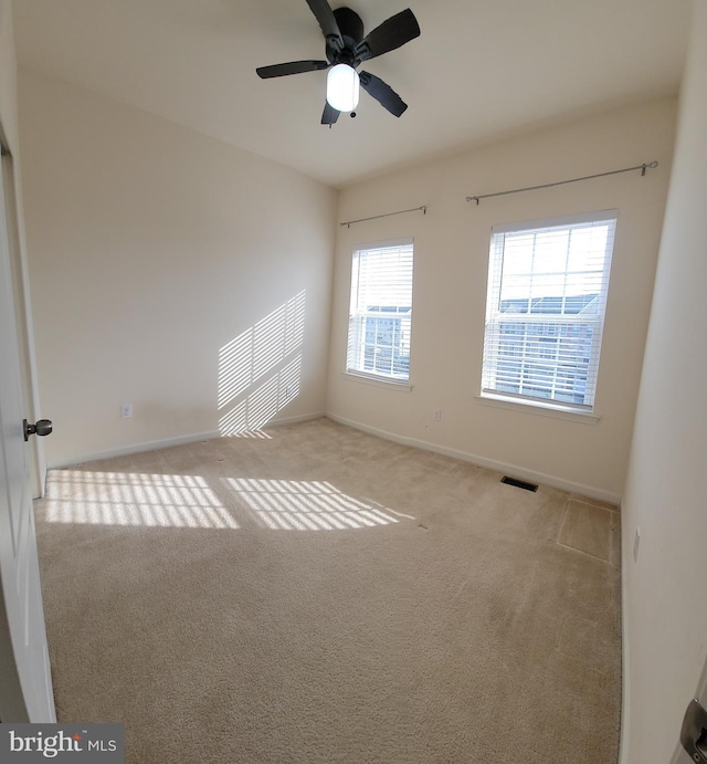 carpeted empty room with a ceiling fan, visible vents, and baseboards