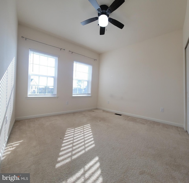 empty room with baseboards, visible vents, and light colored carpet