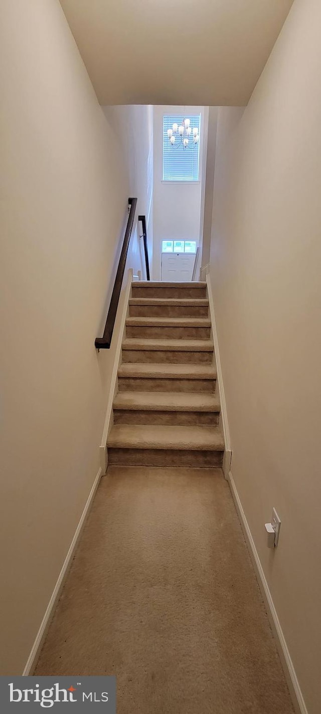 stairs featuring carpet flooring, a notable chandelier, and baseboards