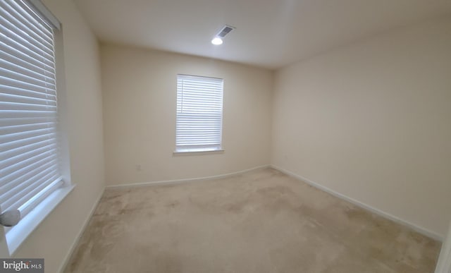 empty room with light carpet, visible vents, and baseboards