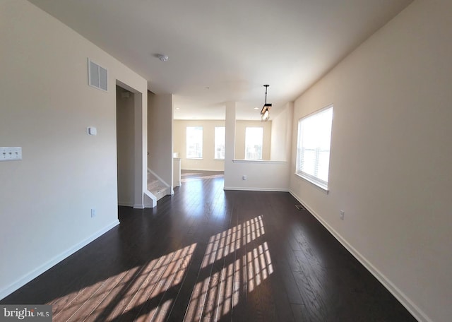 unfurnished living room featuring dark wood-style floors, stairway, visible vents, and baseboards