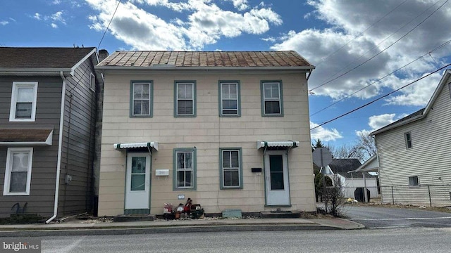 view of front of house featuring entry steps, metal roof, and fence