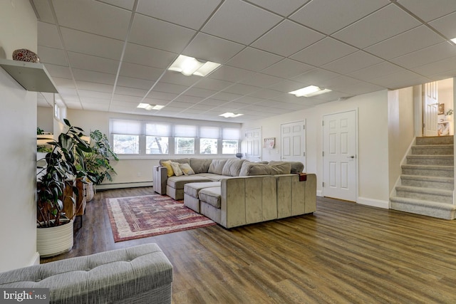 living area featuring a baseboard heating unit, a paneled ceiling, dark wood-style flooring, and stairway