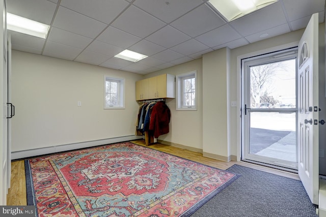 entryway with light wood finished floors, baseboard heating, a drop ceiling, and baseboards