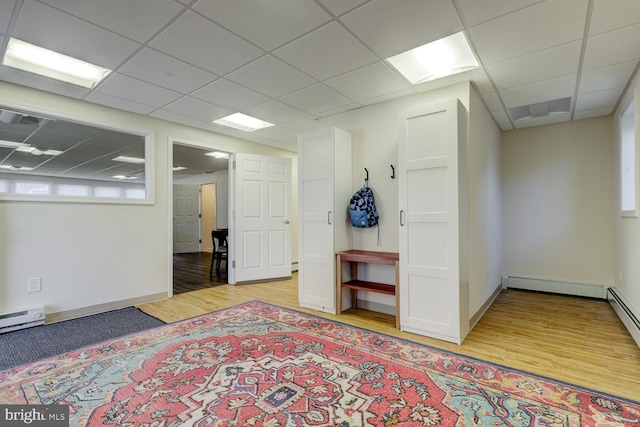 spare room with a paneled ceiling, light wood-style flooring, and baseboards