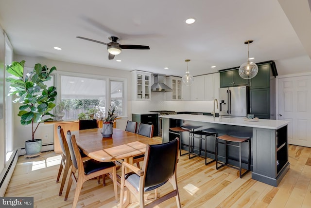 dining space with a ceiling fan, a baseboard radiator, light wood-style flooring, and recessed lighting