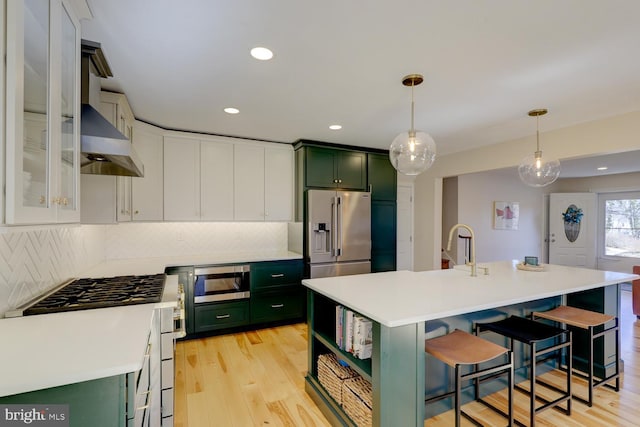 kitchen with light wood finished floors, appliances with stainless steel finishes, light countertops, and green cabinetry