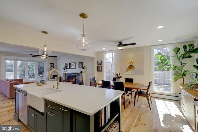 kitchen with light wood finished floors, a fireplace, open floor plan, and a sink