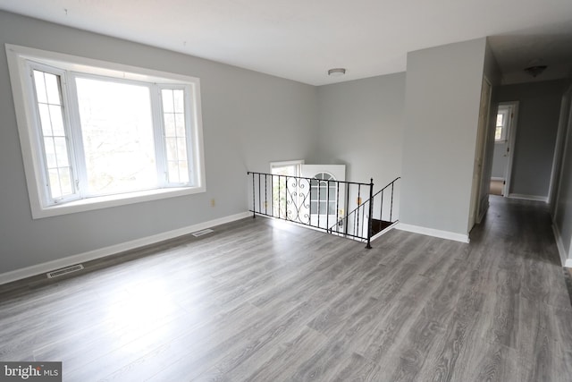 empty room featuring wood finished floors, visible vents, and baseboards