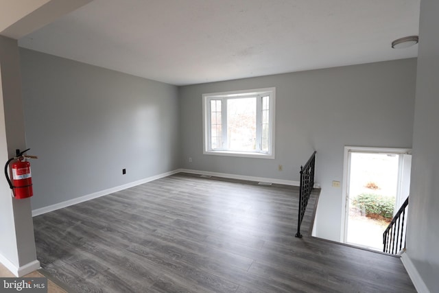 interior space featuring dark wood-type flooring, baseboards, and stairs