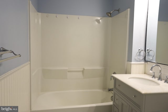 full bath with wainscoting, vanity, and shower / tub combination