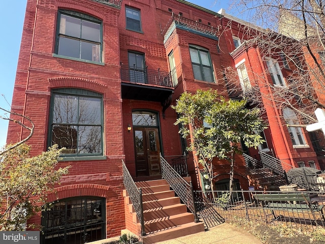 view of front facade with french doors, brick siding, and fence