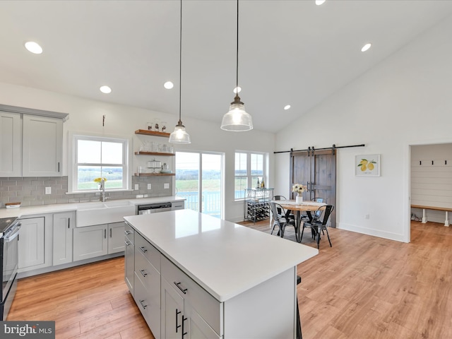 kitchen with a center island, light countertops, a barn door, light wood-style floors, and a sink