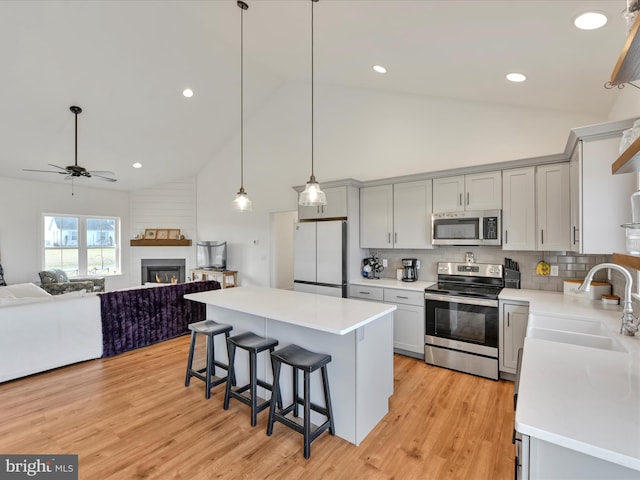 kitchen featuring a kitchen breakfast bar, stainless steel appliances, light countertops, and a sink