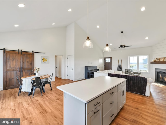 kitchen with light wood-type flooring, light countertops, a glass covered fireplace, open floor plan, and a center island