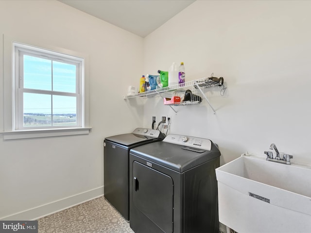 washroom with a sink, baseboards, independent washer and dryer, and laundry area