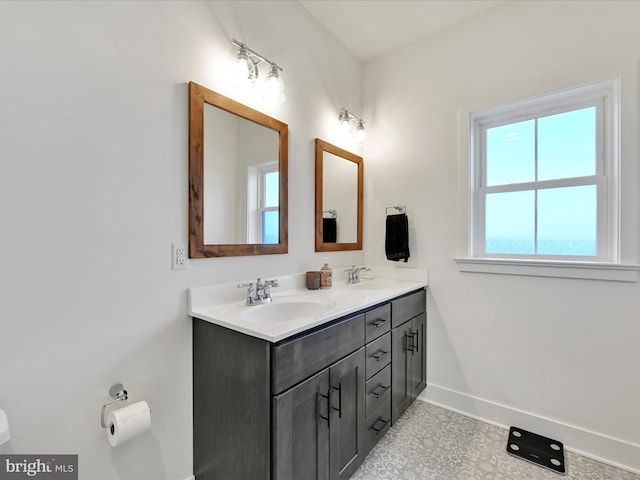 bathroom featuring double vanity, toilet, baseboards, and a sink