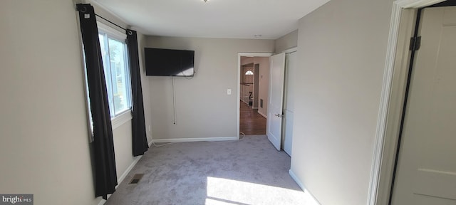 unfurnished bedroom featuring baseboards, multiple windows, visible vents, and light colored carpet