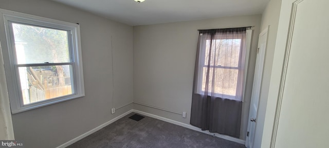 empty room featuring dark colored carpet and baseboards