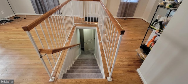 staircase featuring wood finished floors and baseboards