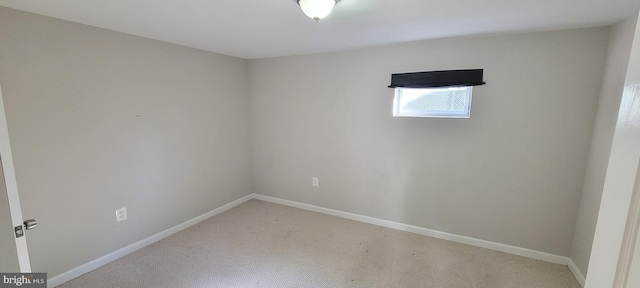 spare room featuring light carpet and baseboards