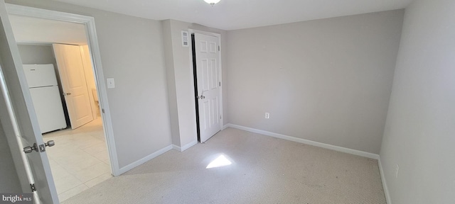 unfurnished bedroom with baseboards, a closet, and freestanding refrigerator