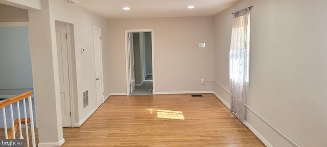 spare room with light wood-type flooring, a healthy amount of sunlight, and visible vents