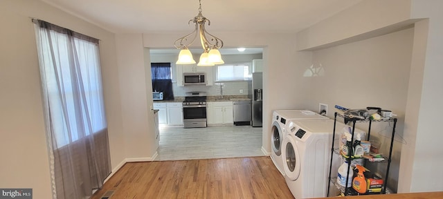 washroom with washing machine and dryer, laundry area, a sink, baseboards, and light wood-style floors