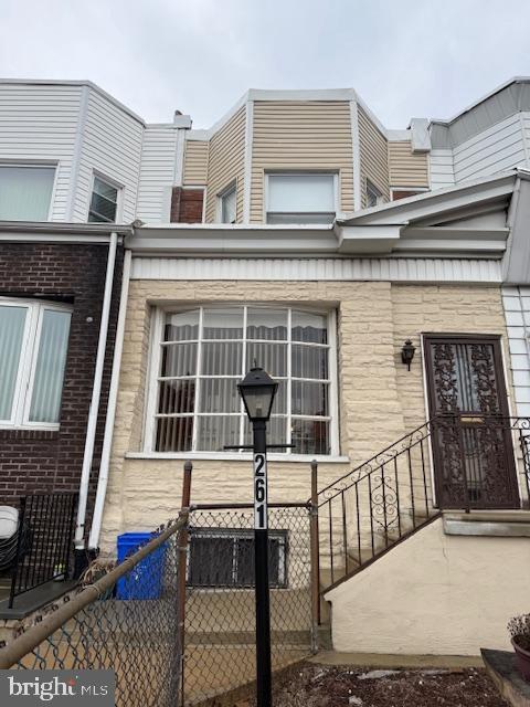 doorway to property with stone siding and fence