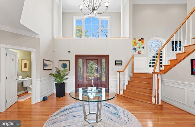 entryway featuring a notable chandelier, ornamental molding, stairs, and wood finished floors