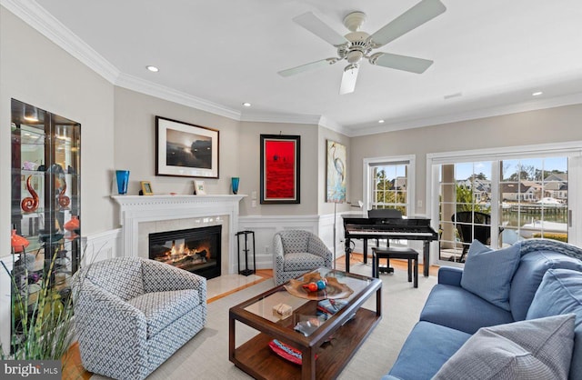 living room with crown molding, recessed lighting, wainscoting, a fireplace, and a ceiling fan