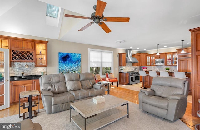 living room with indoor wet bar, light wood-style flooring, and ceiling fan