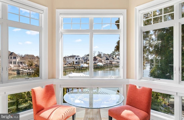 sunroom / solarium featuring a water view and a residential view