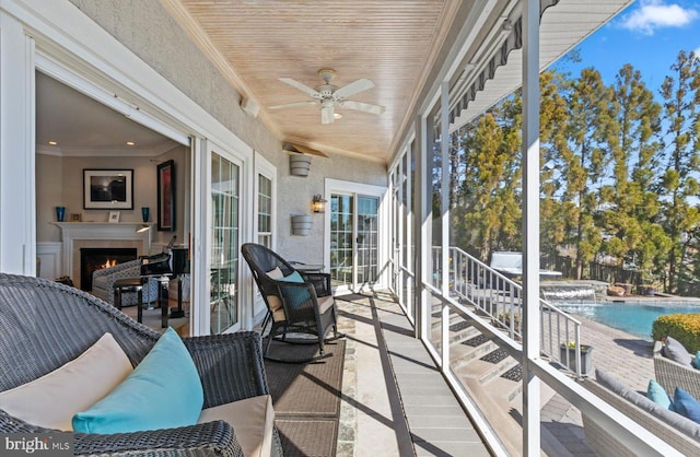 sunroom featuring a lit fireplace and ceiling fan