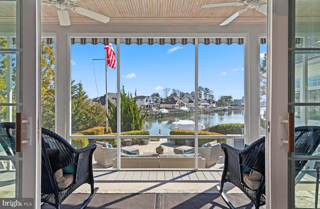 sunroom / solarium with wood ceiling, a ceiling fan, and a water view