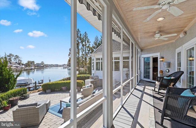 sunroom featuring a ceiling fan, wood ceiling, a water view, and a wealth of natural light