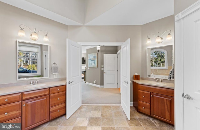 bathroom featuring a sink, stone finish flooring, baseboards, and two vanities