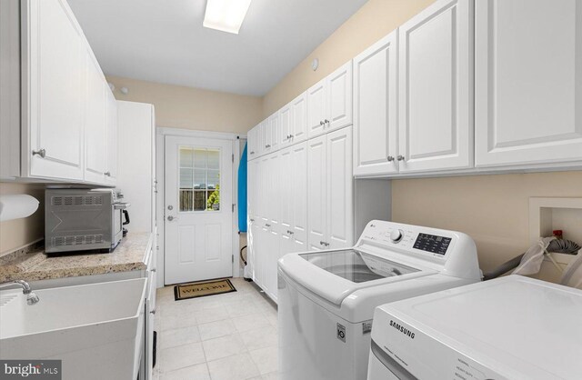 washroom with a sink, cabinet space, and washer and clothes dryer