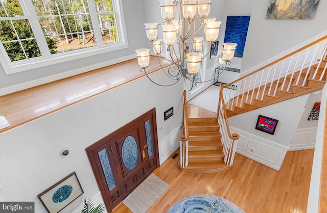 entryway with visible vents, a notable chandelier, wood finished floors, a decorative wall, and stairs