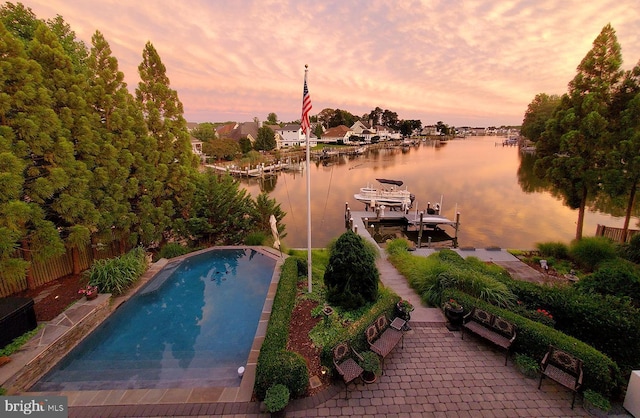 view of swimming pool with a fenced in pool, a water view, boat lift, and a dock