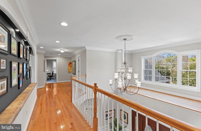 hallway featuring light wood-type flooring, an upstairs landing, ornamental molding, recessed lighting, and a chandelier