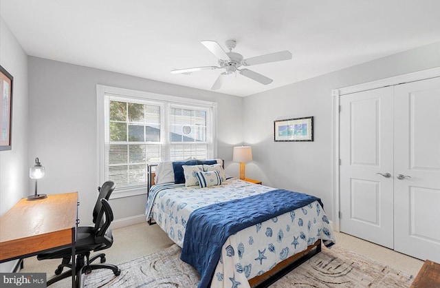 bedroom with a closet, baseboards, light colored carpet, and a ceiling fan