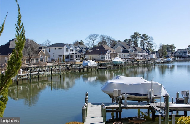 dock area with boat lift, a residential view, and a water view