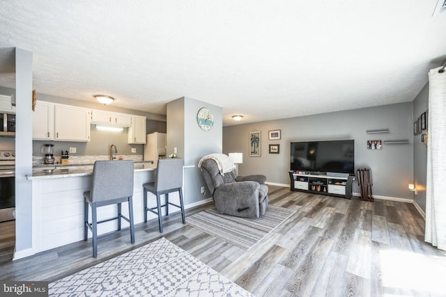 living room with visible vents, a textured ceiling, baseboards, and wood finished floors