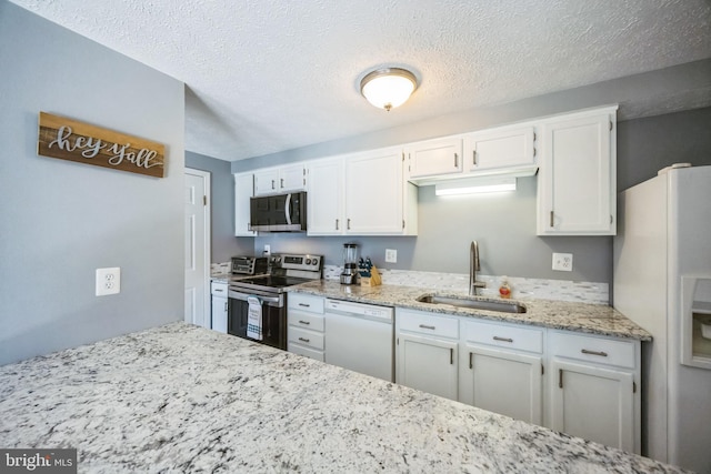 kitchen featuring a sink, light stone counters, appliances with stainless steel finishes, and white cabinetry