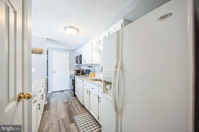 kitchen featuring light stone countertops, dark wood-style flooring, appliances with stainless steel finishes, a textured ceiling, and white cabinetry